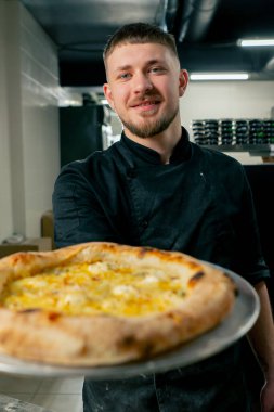 Profesyonel mutfakta, bir pizzacının kapısında şef taze pişmiş pizza hazırlar.