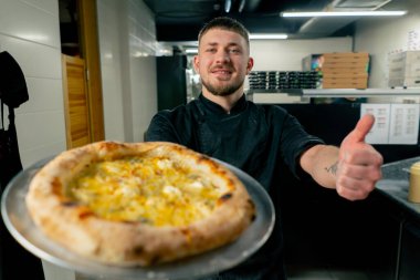 Profesyonel mutfakta, bir pizzacının kapısında şef taze pişmiş pizza hazırlar.