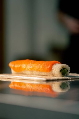 Profesyonel bir mutfağa yakın durduğunda şef, rulo yapmak için paspasın üzerine kırmızı balıklı suşi serer.