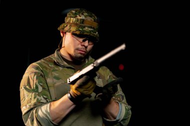 Profesyonel atış poligonunda yakın plan askeri eğitimci silah dolduruyor.