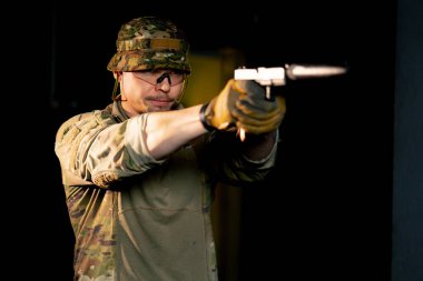Profesyonel bir atış talimine yakın cephaneli askeri eğitimci silahla nişan alır.