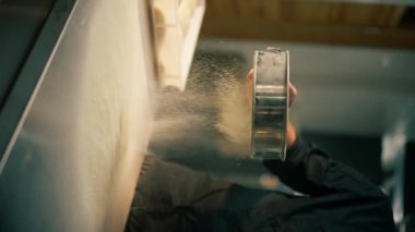 Bir pizzacıda profesyonel bir mutfakta dikey çekim yaparken şef masayı un ile temizler.