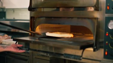 Bir pizzacının profesyonel mutfağında pastırmalı pizza fırından hazırlanır.
