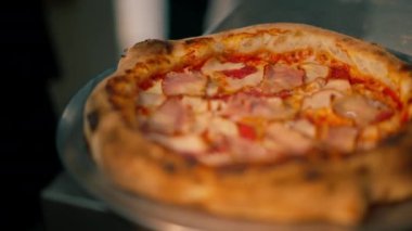 Profesyonel bir mutfağa yakın plan. Masada yeni hazırlanmış pizza var.