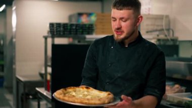 Profesyonel mutfakta, bir pizzacının kapısında şef taze pişmiş pizza hazırlar.