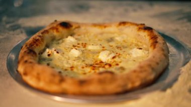 Profesyonel bir mutfağa yakın plan. Masada yeni hazırlanmış pizza var.