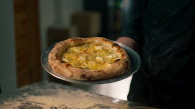 Profesyonel mutfakta, bir pizzacının kapısında şef taze pişmiş pizza hazırlar.