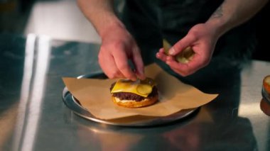 Profesyonel bir mutfakta, pizzacıda şef masaya bir burger koyar.