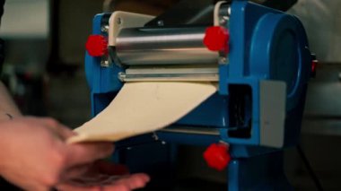 Profesyonel bir mutfakta kapanış. Şef hamuru ev yapımı makarna için özel bir makineye sarar.