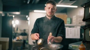 Profesyonel bir mutfakta şef büyük bir tavada sebzeli wog eriştesi hazırlar.