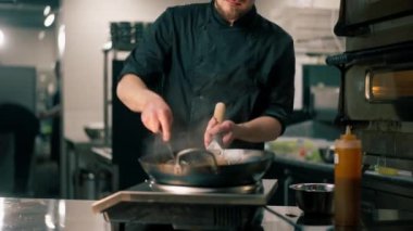Profesyonel bir mutfakta şef büyük bir tavada sebzeli wog eriştesi hazırlar.