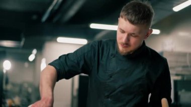 Profesyonel bir mutfakta yakın plan çekimde şef, yabani erişteleri derin tabakta sebzelerle süslüyor.