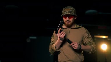 Profesyonel bir atış poligonunda askeri eğitmen ateş etmeye hazır bir silahı dolduruyor. 