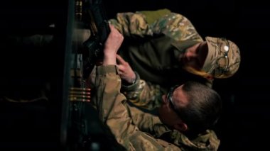 Profesyonel bir atış menzilinde, dikey bir video. Profesyonel bir avcı uçağı bir NATO saldırı tüfeği kuruyor.