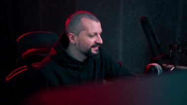 Kayıt odasının karanlığında stüdyoda neon ışıkla birlikte ses mühendisi konsolda çalışır sesi ayarlar ve sesi karıştırır.