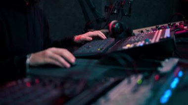 Kayıt odasının karanlığında stüdyoda neon ışıkla birlikte ses mühendisi konsolda çalışır sesi ayarlar ve sesi karıştırır.