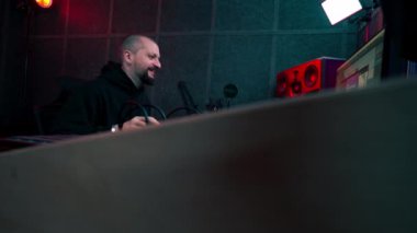 Kayıt odasının karanlığında stüdyoda neon ışıkla birlikte ses mühendisi konsolda çalışır sesi ayarlar ve sesi karıştırır.
