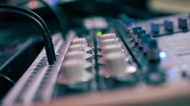 Kayıt odasının karanlığında, stüdyoda neon ışıkla birlikte ses mühendisi uzaktan kumandayla çalışır ve sesi ayarlar.