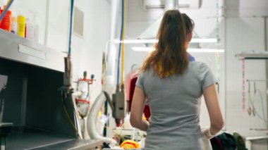 Profesyonel kuru temizlemeci kız beyaz ceketli profesyonel ekipmanında leke bırakıyor.