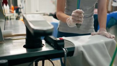 Profesyonel kuru temizlemeci kız beyaz cekette profesyonel ekipmanlara leke sürüyor.