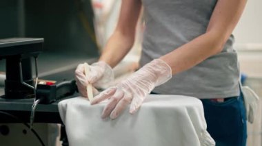 Profesyonel kuru temizlemeciyi kapat. Genç bir kız özel bir kimyasal kalemle lekeyi çıkarır.
