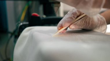 Profesyonel kuru temizlemeciyi kapat. Genç bir kız, özel bir kalemi buharlı kalemle lekesini çıkarır.