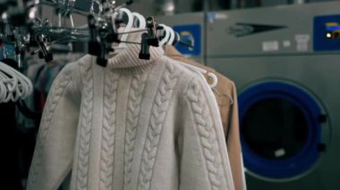 Askılarda farklı tekstil giysileri olan profesyonel kuru temizlemeciyi kapat.