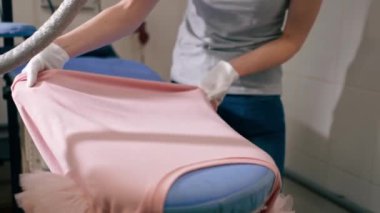 Profesyonel kuru temizlemeci kızı kapatın. Pembeyi profesyonel ütüyle buharla ütüleyin.