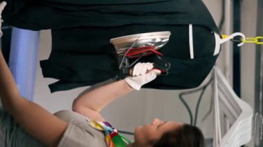 Profesyonel kuru temizlemeci kız siyah bir kazağı buharlı bir askıda ütülüyor.