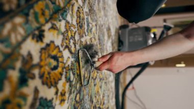 Dairede dikey video kapanıyor. Usta bir temizlikçi, profesyonel bir temizleyici ile halıyı temizliyor.