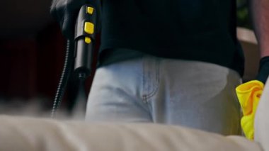 Bir dairede profesyonel temizliği kapatmak. Temizlikçi yıkamadan önce tekstil kanepesini ıslatır.