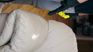Dikey video profesyonel temizliği kapatır bir apartman dairesinde bir temizlikçi yıkanmadan önce tekstil kanepesini ıslatır
