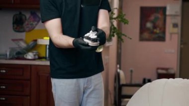 Bir apartmanın profesyonel temizliği bir temizlikçi deri bir kanepeyi cilayla parlatır.