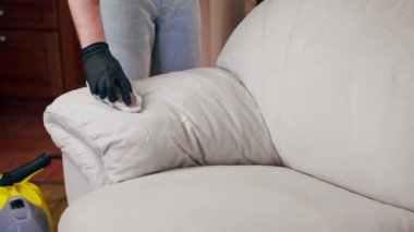 Bir apartmanın profesyonel temizliği. Bir temizlikçi deri bir kanepeyi cilayla parlatır.