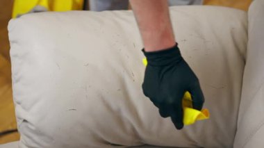 Kanepenin deri kısmını silmek için profesyonel bir apartman temizleyicisini kapat.