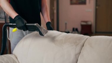 Bir dairede profesyonel temizliği kapatmak. Temizlikçi yıkamadan önce tekstil kanepesini ıslatır.