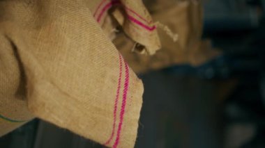 Bir kahve kızartma fabrikasının dikey görüntüsü. Bir işçi bir çanta açar ve kavrulmak için yeşil kahve alır.