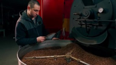 Kahve kızartan bir fabrika işçisi kavrulmuş kahveyi yukarı doğru fırlatıyor.