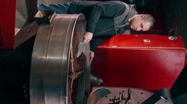 Dikey video bir kahve kızartma fabrikası bir işçi kürekle kavrulmuş kahve dolduruyor.