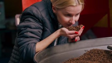Kahve kızartma fabrikasında taze kavrulmuş kahve içen genç bir kızın yakın çekimi.