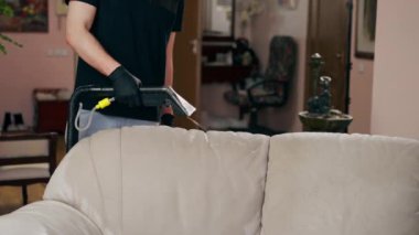 Profesyonel temizlikçi, temizlikçi, yıkamadan önce tekstil kanepesini ıslatır.