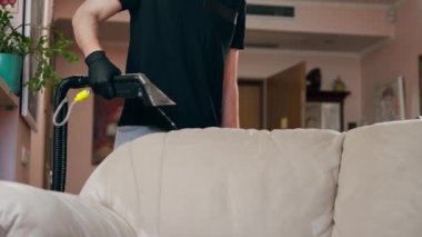 Profesyonel temizlikçi, temizlikçi, yıkamadan önce tekstil kanepesini ıslatır.