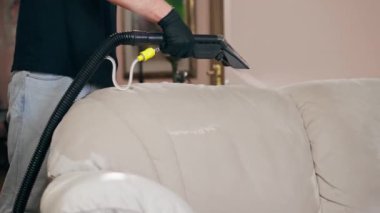 Profesyonel temizlikçi, temizlikçi, yıkamadan önce tekstil kanepesini ıslatır.