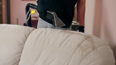 Profesyonel temizlikçi, temizlikçi, yıkamadan önce tekstil kanepesini ıslatır.