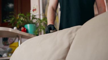 Bir apartman dairesinde profesyonel temizliği kapatır. Temizlikçi tekstil kanepesini fırça ve deterjanla temizler.