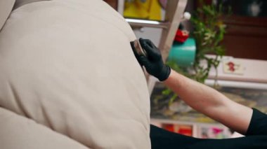 Bir dairede profesyonel temizlik videosu kapanıyor. Temizlikçi tekstil kanepesini fırça ve deterjanla temizliyor.