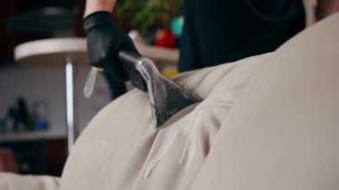 Daire temizleyicisinin profesyonel temizliği deterjan tekstil kanepesiyle süpürülüyor