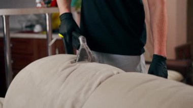 Daire temizleyicisinin profesyonel temizliği deterjan tekstil kanepesiyle süpürülüyor