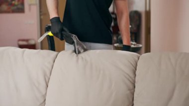 Daire temizleyicisinin profesyonel temizliği deterjan tekstil kanepesiyle süpürülüyor