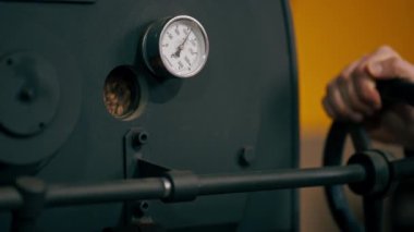 Küçük bir kahve kızartma fabrikasında bir işçi son aşama için davula kahve doldurur.